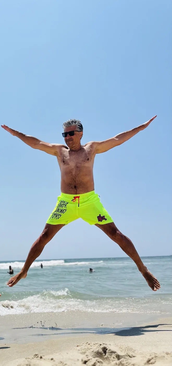 Alex jumping on the beach with arms and legs spread wide